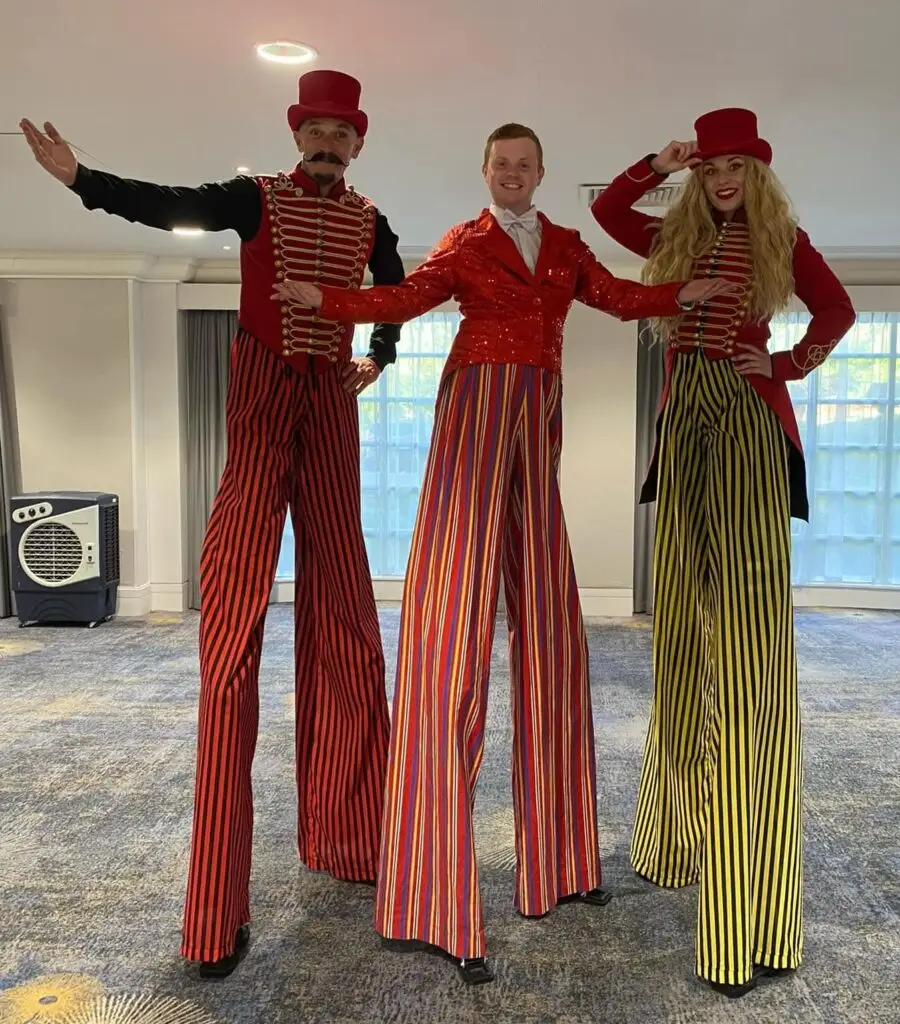 3 circus stilt walkers in brightly coloured costumes