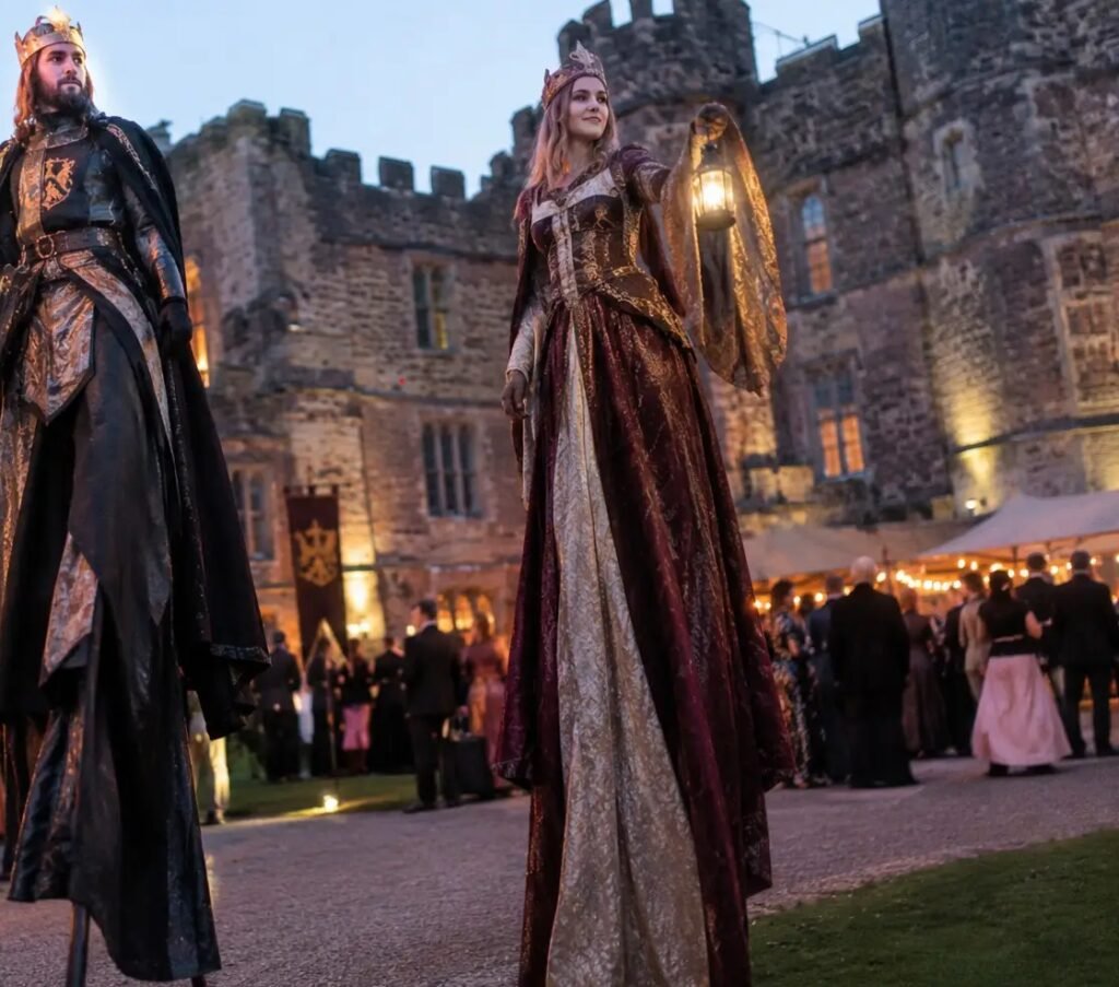 two medieval stilt walkers outside a castle