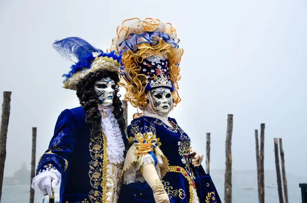 Couple in elaborate Venetian costumes at a traditional masquerade event, showcasing exquisite craftsmanship.